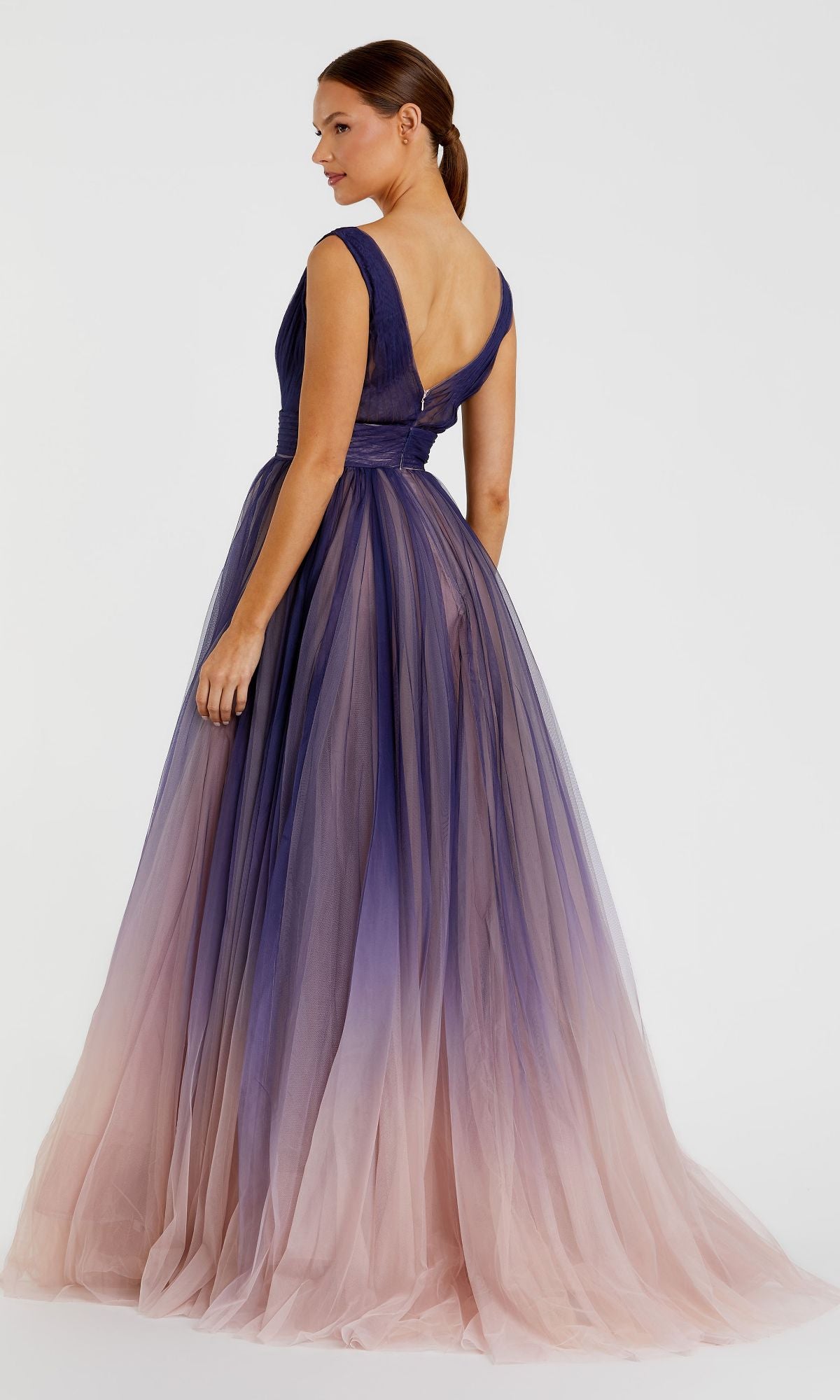 A woman stands against a white background wearing the Indigo Ombre Prom Ball Gown: Mac Duggal 20221—an indigo A-line gown with a deep V-back and ombre tulle fading from dark purple to light pink.
